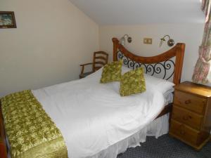 a bedroom with a white bed with a wooden headboard at The Glan Yr Afon Inn in Holywell
