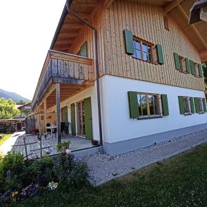 Casa con ventanas con persianas verdes y balcón. en Ferienwohnung Morgenrot, en Pfronten