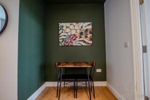 a stool in front of a green wall with a painting at Guest Homes - Foley House Apartments in Great Malvern