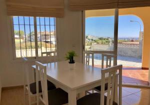 Una mesa y sillas blancas en una habitación con ventanas. en Villa Siva, en Torrox Costa