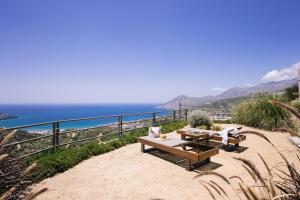 a picnic table and chairs on a hill overlooking the ocean at Villa Stella Suites in Plakias