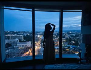 a woman standing in front of a window looking at a city at AEON Towers Davao in Davao City