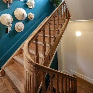 un escalier avec des balustrades en bois et des murs bleus dans l'établissement Couleur basilic, à Rochefort