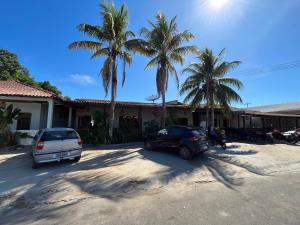 two cars parked in front of a house with palm trees at Local Hostel Novo Airão in Novo Airão