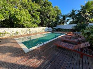 a swimming pool with benches and a wooden deck at Local Hostel Novo Airão in Novo Airão