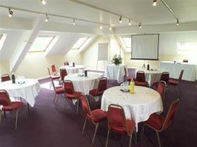 una sala de conferencias con mesas, sillas y una pantalla en Three Counties Hotel, en Hereford