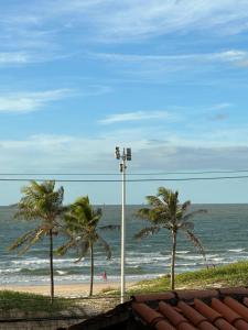 a beach with two palm trees and the ocean at Apês Completos na Litorânea l Cozinha e Conforto l Ferreira Hospedagens in São Luís