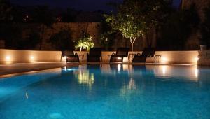 uma piscina à noite com cadeiras e luzes em Mensija Valley Residences em St. Julian's