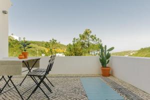 a patio with a table and chairs on a balcony at Sãone Guesthouse - Coworking & Retreat Location in Ericeira