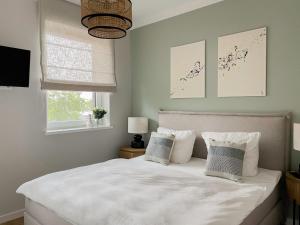 um quarto com uma cama com lençóis brancos e almofadas em My Baltic Sea - Ferienwohnungen im Saltwater House em Scharbeutz