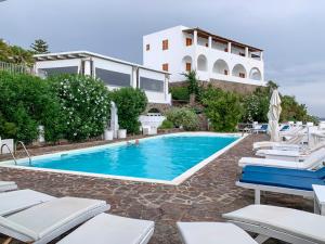 a swimming pool with lounge chairs and a house at Basiluzzo Resort in Panarea