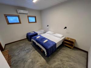 a bedroom with two beds and two windows at Local Hostel Novo Airão in Novo Airão