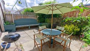 einen Tisch und Stühle mit einem Sonnenschirm und einem Grill in der Unterkunft Oyster Cottage Braunton | Sleeps 6 | Dog Friendly in Braunton