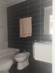 een zwart betegelde badkamer met een toilet en een wastafel bij Urbanización Marenia - Las Marinas, Denia in Denia