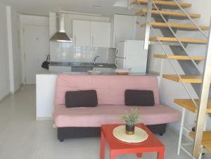 een woonkamer met een roze bank en een tafel bij Urbanización Marenia - Las Marinas, Denia in Denia