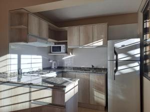 a kitchen with wooden cabinets and a stainless steel refrigerator at Departamentos en Tupungato in Tupungato