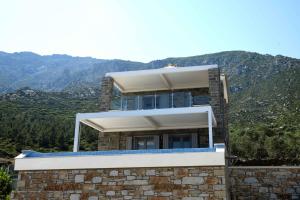 a house on a hill with mountains in the background at Tsapelas Villas in Agios Kirykos