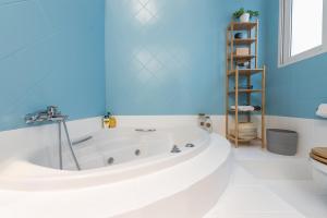 La salle de bains est pourvue d'une baignoire et d'un mur bleu. dans l'établissement Private Loft Suite with stunning view of Acropolis, à Athènes