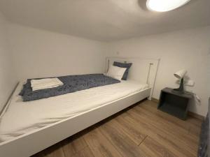 ein weißes Bett in einem Zimmer mit einem Nachttisch in der Unterkunft MaNo Guesthouse Budapest in Budapest