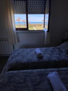 a bed with a window with a view of the beach at Complejo San Cristobal in Santa Clara del Mar