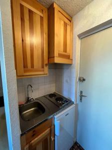 a small kitchen with a sink and wooden cabinets at Studio cosy à vue Panoramique in Puy-Saint-Vincent