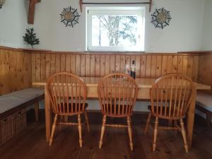 uma mesa de madeira com três cadeiras e uma janela em Rustical cottage with indoor fireplace em Sodražica