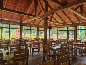 un comedor con mesas, sillas y ventanas en Rafting Camp Tara 87, en Hum