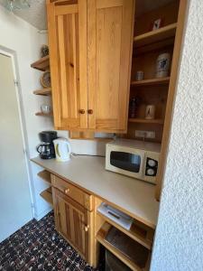 a kitchen with wooden cabinets and a microwave at Studio cosy à vue Panoramique in Puy-Saint-Vincent