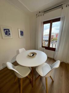 una mesa y sillas blancas en una habitación con ventana en Blanco y Añil Plaza, en Valdepeñas