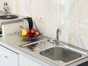 a kitchen with a sink and a bowl of fruit at Apartments Klajdi in Sarandë