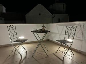 two chairs and a table in front of a white wall at La Casa Al Mare in Polignano a Mare
