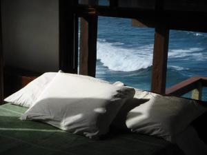 uma cama com almofadas brancas e vista para o oceano em Casa no Pontal do Atalaia - ESPETACULAR em Arraial do Cabo