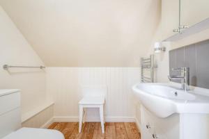 Baño blanco con lavabo y taburete en Stable Cottage 2 bedrooms with gorgeous views, en Dunblane