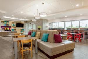sala de estar con sofá, mesas y sillas en Home2 Suites By Hilton Vero Beach I-95, en West Vero Corridor