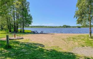 a park with two picnic tables next to a lake at Cozy Home In rebro With Wifi in Örebro