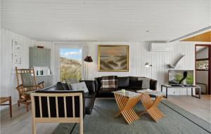 un soggiorno con divano nero e sedie di Gorgeous Home In Hvide Sande With Sauna a Havrvig