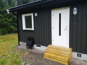 een zwart huis met een witte deur en een trap bij Lys og moderne leilighet i Bø. 