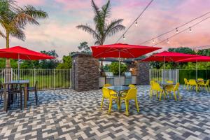 a patio with tables and chairs and red umbrellas at Home2 Suites By Hilton Vero Beach I-95 in West Vero Corridor