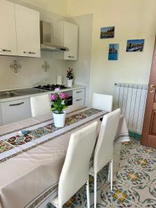 una cocina con una mesa con sillas blancas y flores en Luxury Apartment Vanacore, en Castelnuovo Cilento
