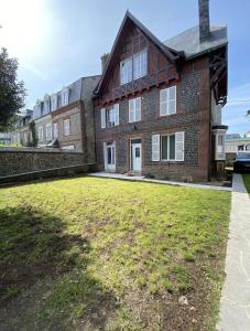 een groot bakstenen huis met een grasveld ervoor bij Villa L'Anse - 1er étage in Étretat