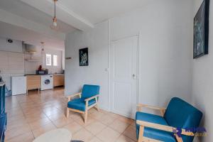 uma sala de estar com duas cadeiras azuis e uma cozinha em L'Améthyste City WIFI em Perpignan