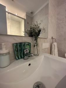 a white bathroom sink with a vase of flowers on it at Plaza Spain Barcelona Apartments in Barcelona