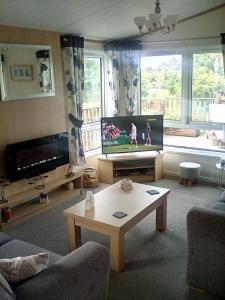 a living room with a tv and a coffee table at LakeView Lodge Trevella Park in Crantock