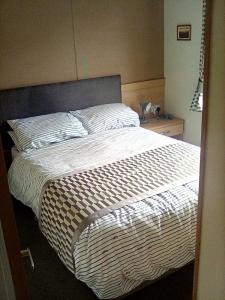 a bedroom with a large bed with a white comforter at LakeView Lodge Trevella Park in Crantock