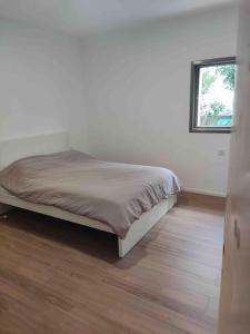 a bed in a white room with a wooden floor at Maison herzliyah pitouach 5 minutes à pied la plage in Herzliya