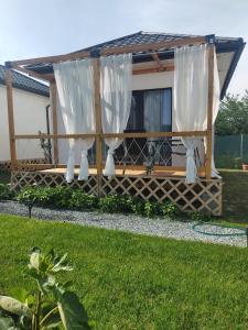 a gazebo with white curtains in a yard at Flip Flop Bungalows in Vadu