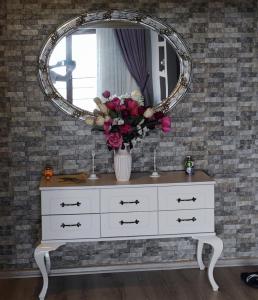 a white dresser with a mirror and flowers on it at Ayliya hause in Akcaabat