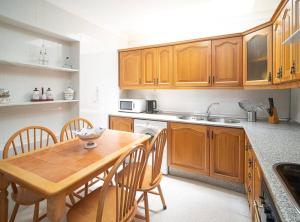 una cocina con armarios de madera y una mesa y sillas de madera. en SibsSanlucar Albero - Ideal Familias - Centro - Playa Piletas en Sanlúcar de Barrameda