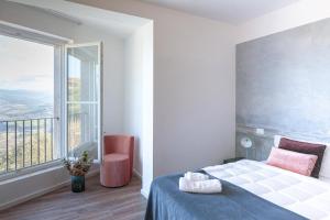 a bedroom with a bed and a large window at Corte Francigena in Montalcino