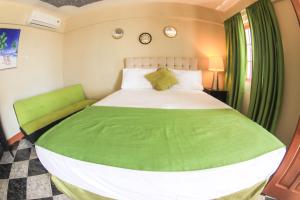 a bedroom with a large bed with a green blanket at Kaiser Hotel- Negril West End in Negril